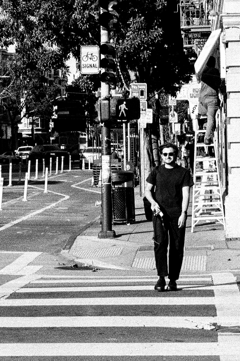 Black and white picture of me (Pablo Olavarrieta) walking across a crosswalk in San Francisco, CA.